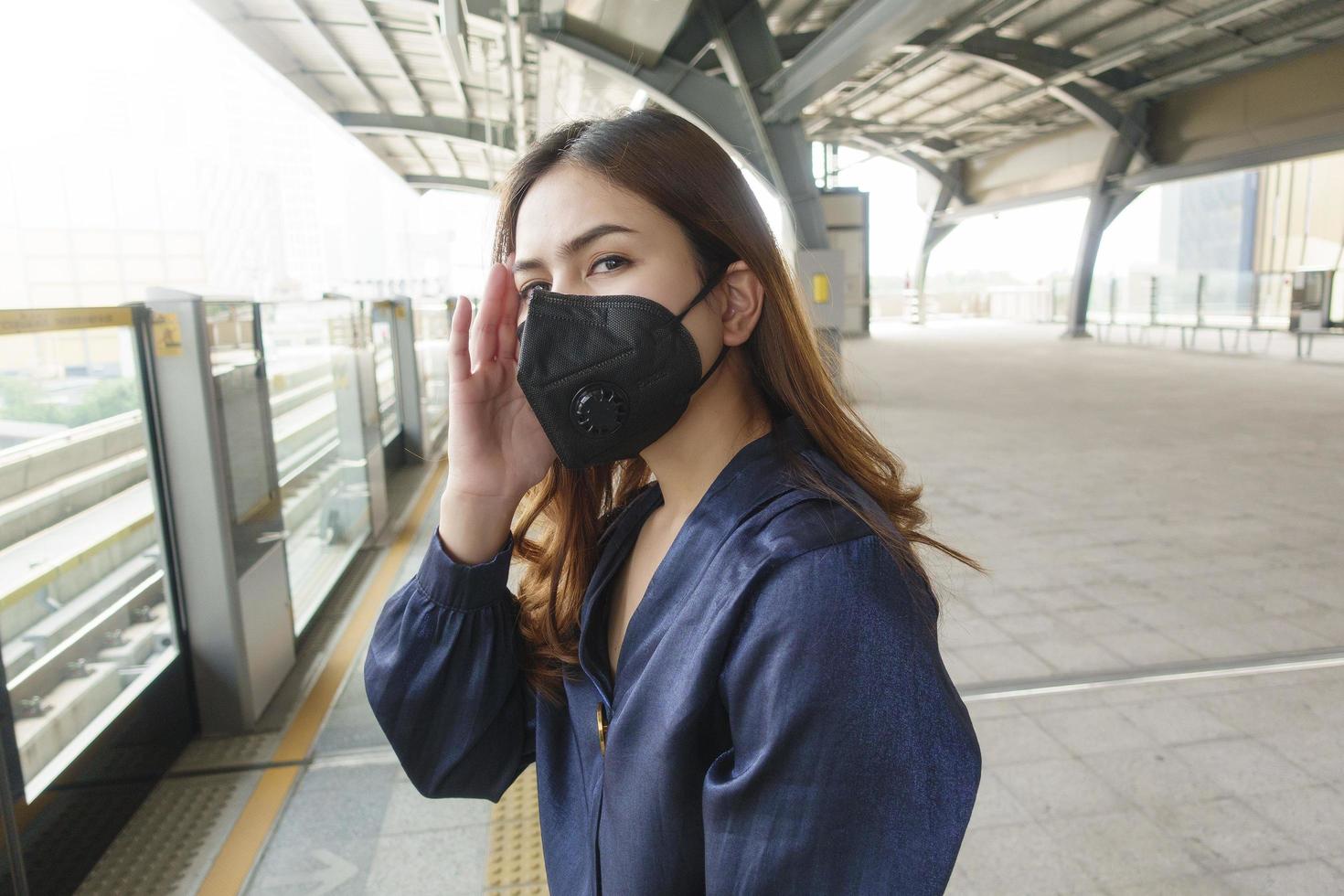 mooie vrouw die een antistofmasker draagt, beschermt luchtvervuiling en pm 2.5 op straatstad foto