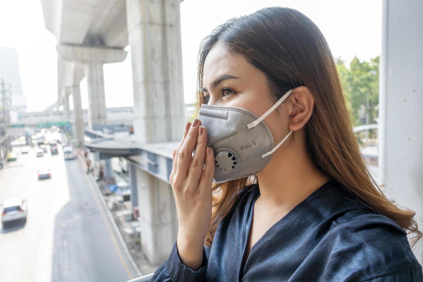 mooie vrouw die een antistofmasker draagt, beschermt luchtvervuiling en pm 2.5 op straatstad foto