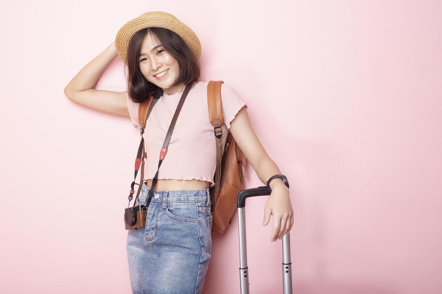 gelukkige aziatische vrouwentoerist op roze achtergrond foto