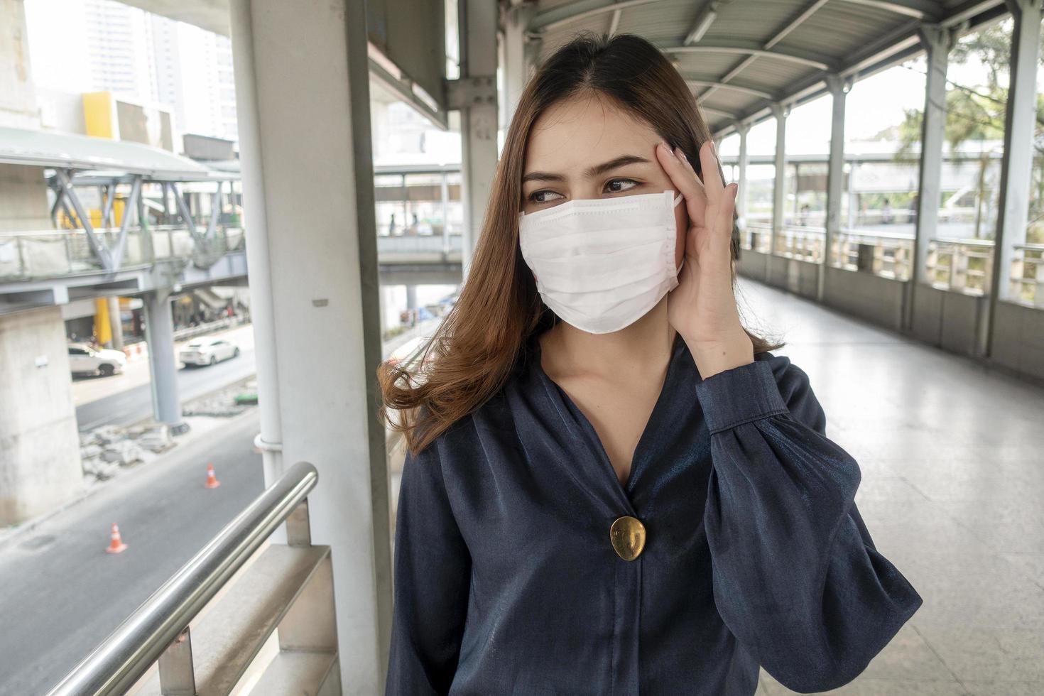 mooie vrouw die een antistofmasker draagt, beschermt luchtvervuiling en pm 2.5 op straatstad foto