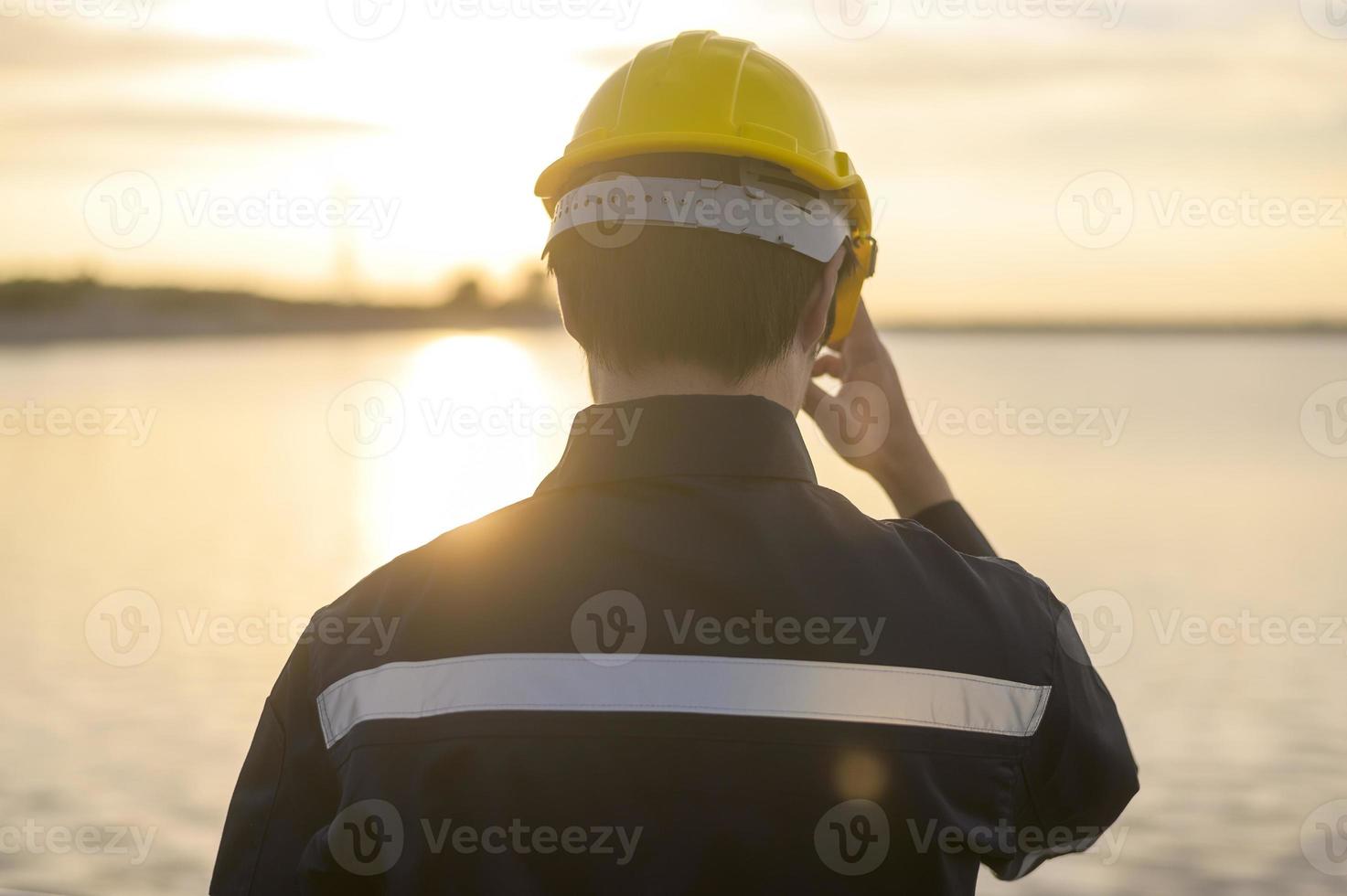een mannelijke ingenieur die een beschermende helm draagt bij zonsondergang. foto