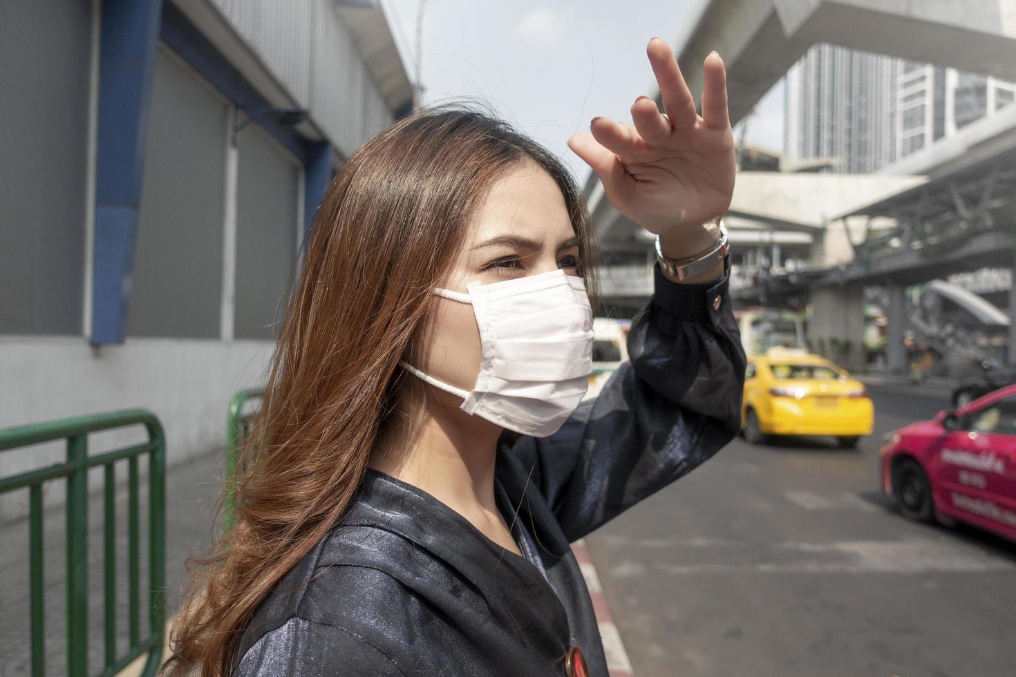 mooie vrouw die een antistofmasker draagt, beschermt luchtvervuiling en pm 2.5 op straatstad foto