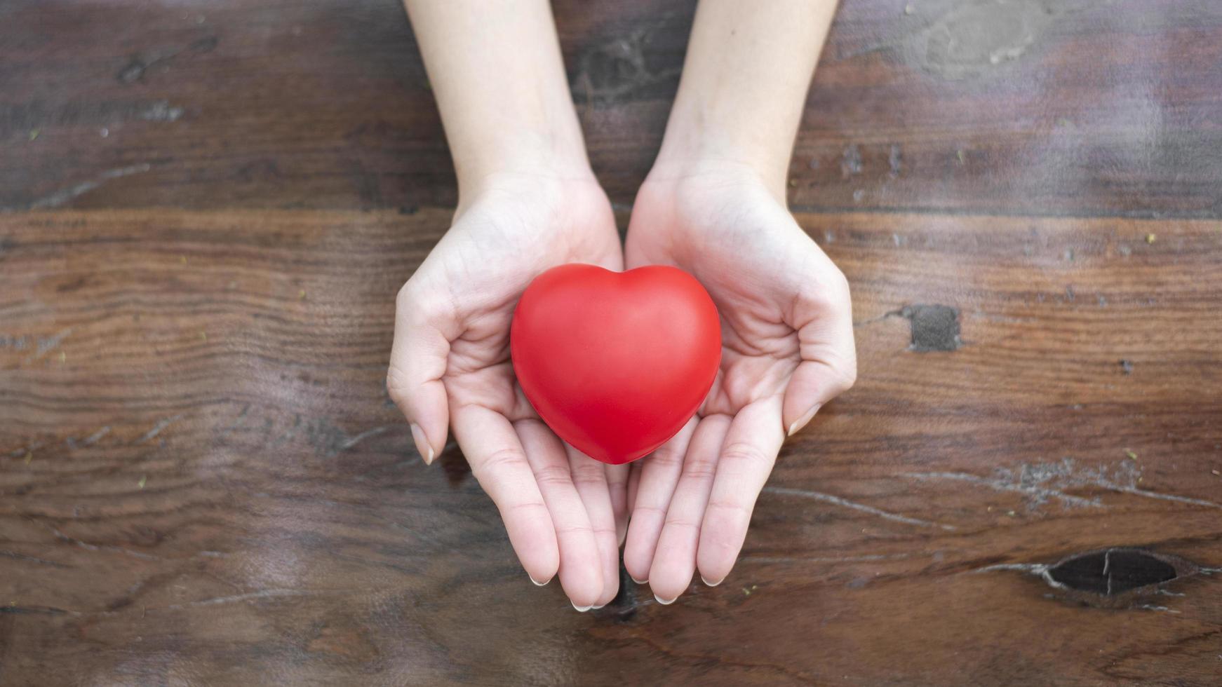 vrouwenhand houdt rood hart, liefde en gezondheidszorgconcept vast foto