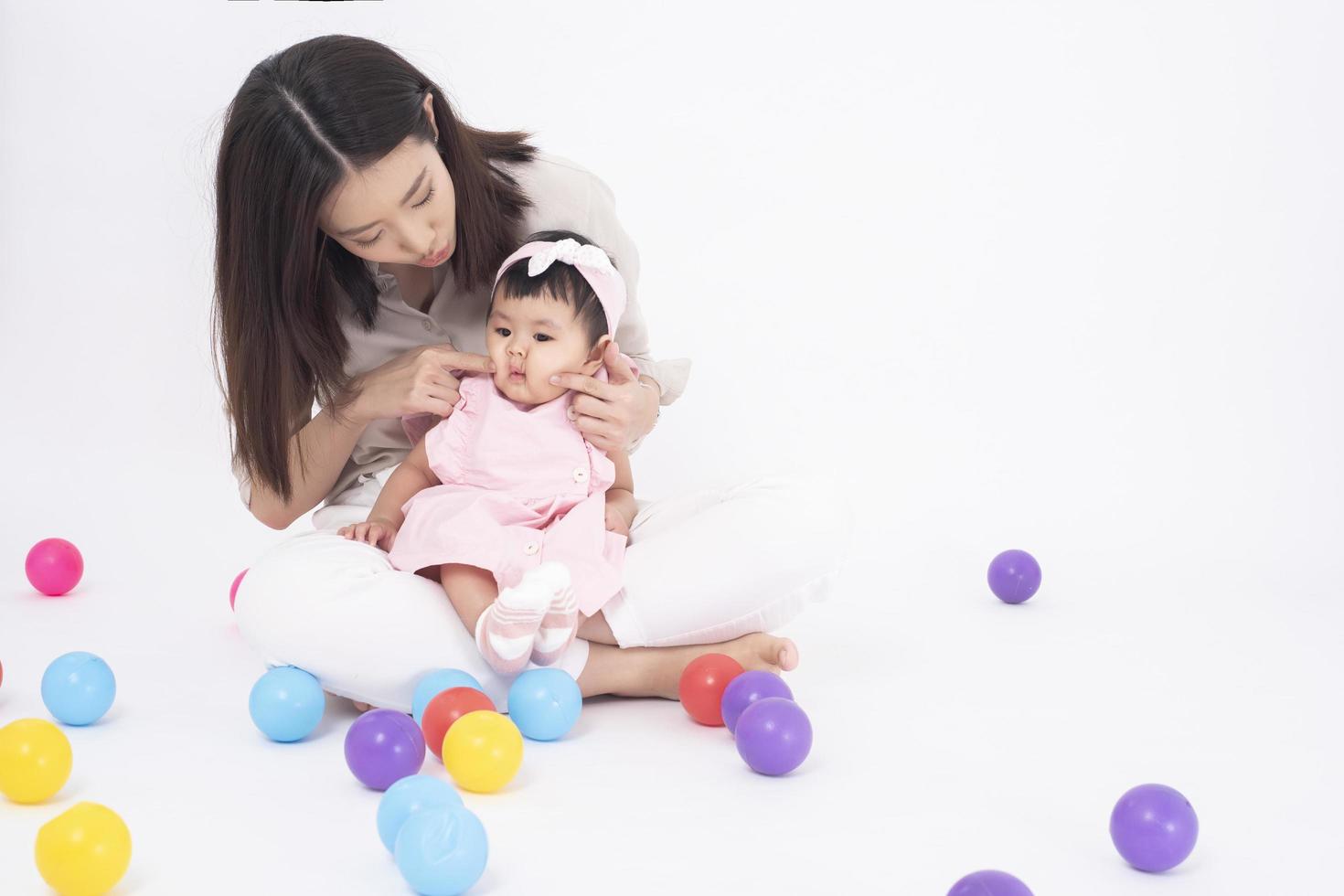 Aziatische moeder en schattig babymeisje zijn blij op een witte achtergrond foto