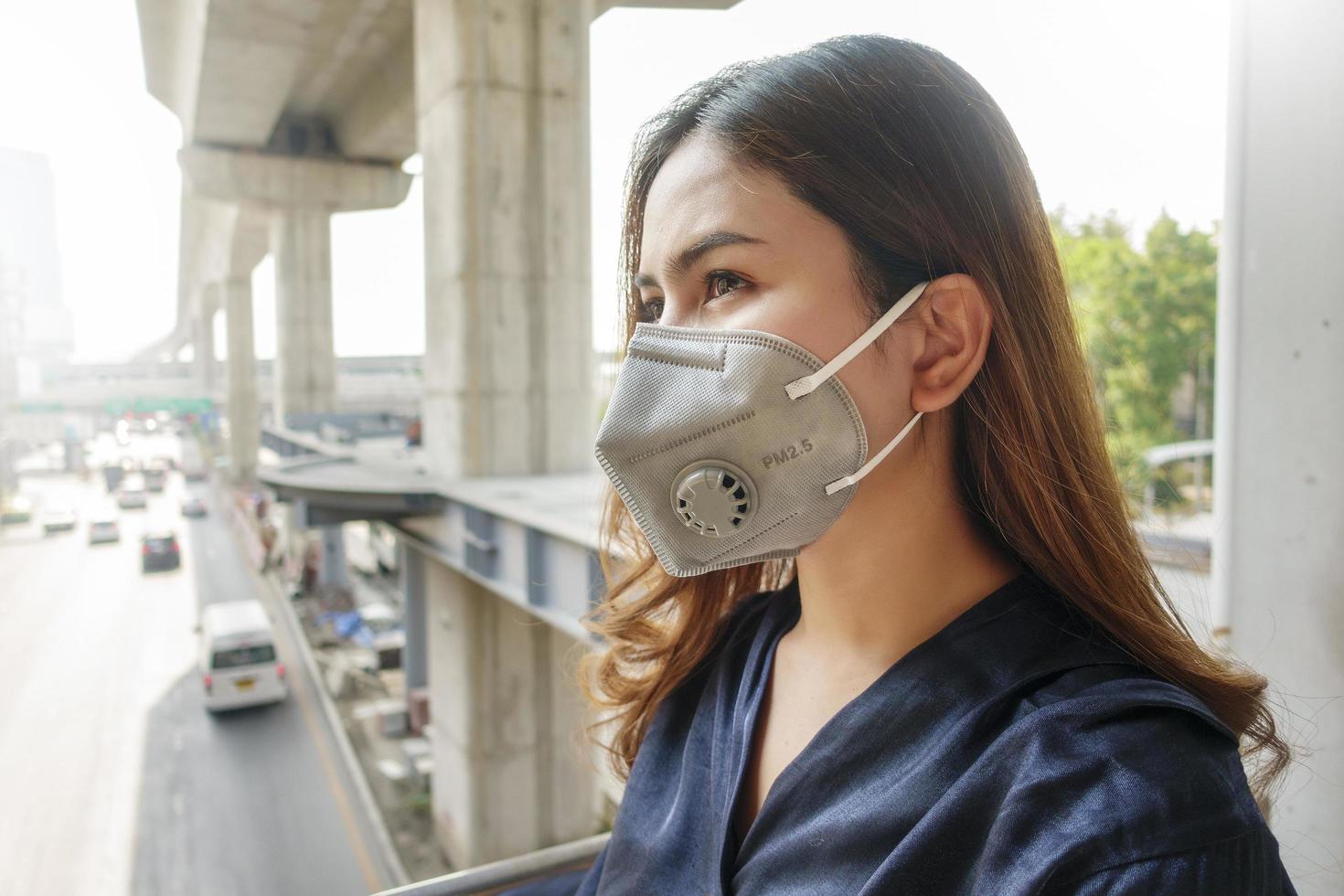 mooie vrouw die een antistofmasker draagt, beschermt luchtvervuiling en pm 2.5 op straatstad foto