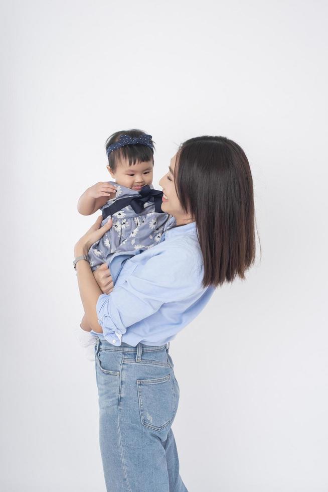 Aziatische moeder en schattig babymeisje zijn blij op een witte achtergrond foto