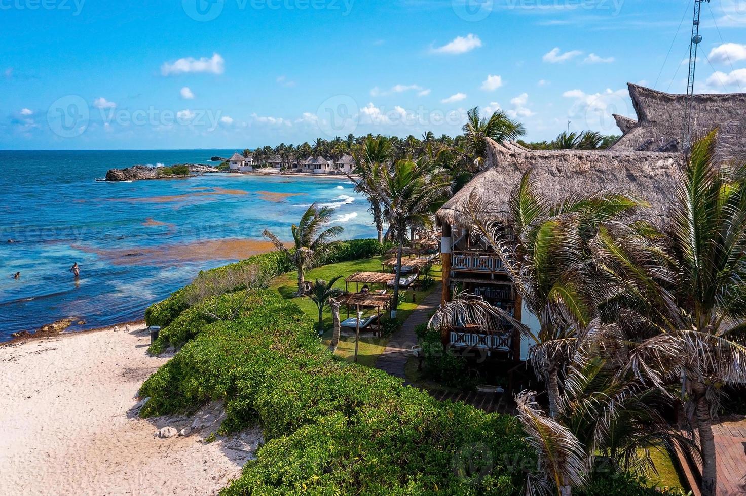 luchtfoto tulum kustlijn aan het strand met een magische Caribische zee en kleine hutten aan de kust. foto