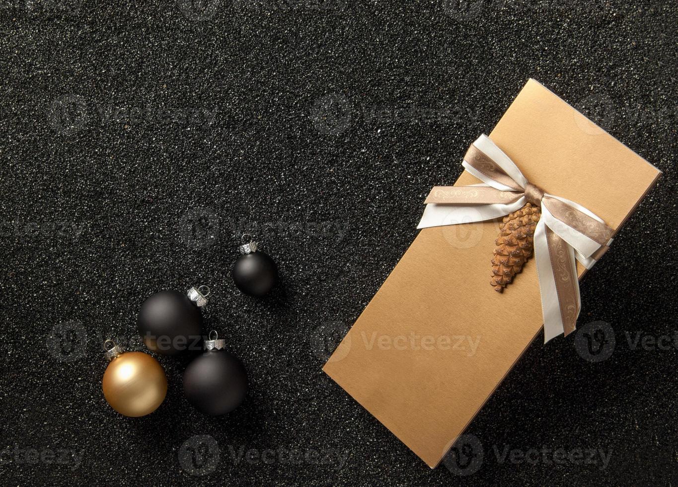 cadeauboekje met kerstboomversieringen op een zwarte korrelige achtergrond. flyer met lint op zwarte korrelige achtergrond foto