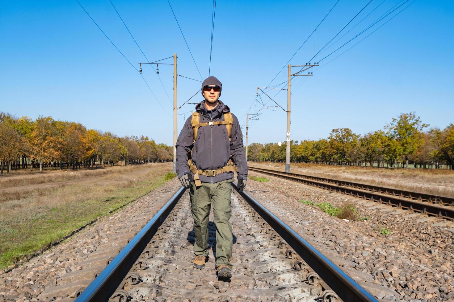 mannelijke reiziger met tactische en militaire uitrusting loopt alleen op zonnige dag foto