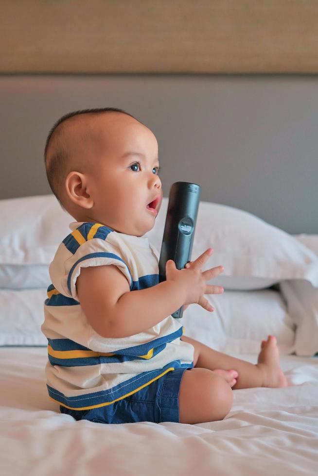 portret van een gelukkige 6 maanden oude Aziatische babyjongen die op bed zit te spelen foto