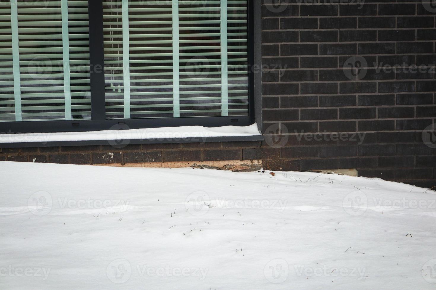 grote sneeuwbank bij raam met hoizontale jaloezieën foto