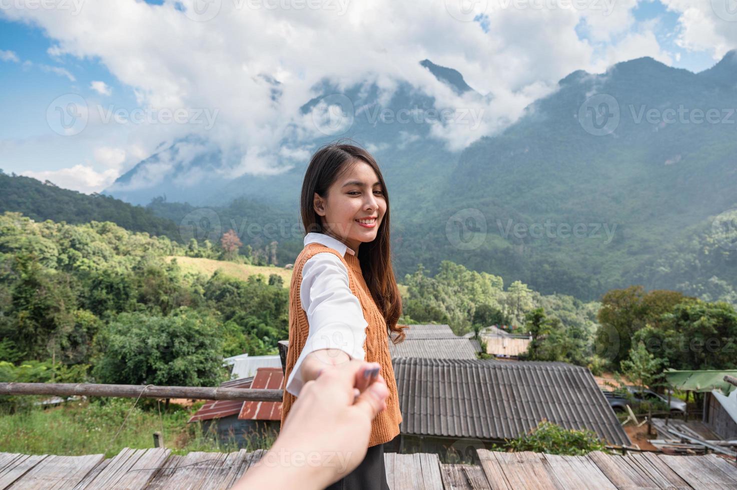 jonge aziatische vrouw die haar vriendje hand in hand houdt terwijl ze geniet van het uitzicht op de bergen op de heuvel bij het uitkijkpunt in chiang dao foto