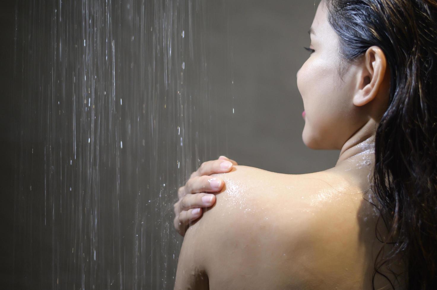 jonge mooie vrouw die thuis een douche neemt in een badkamer foto