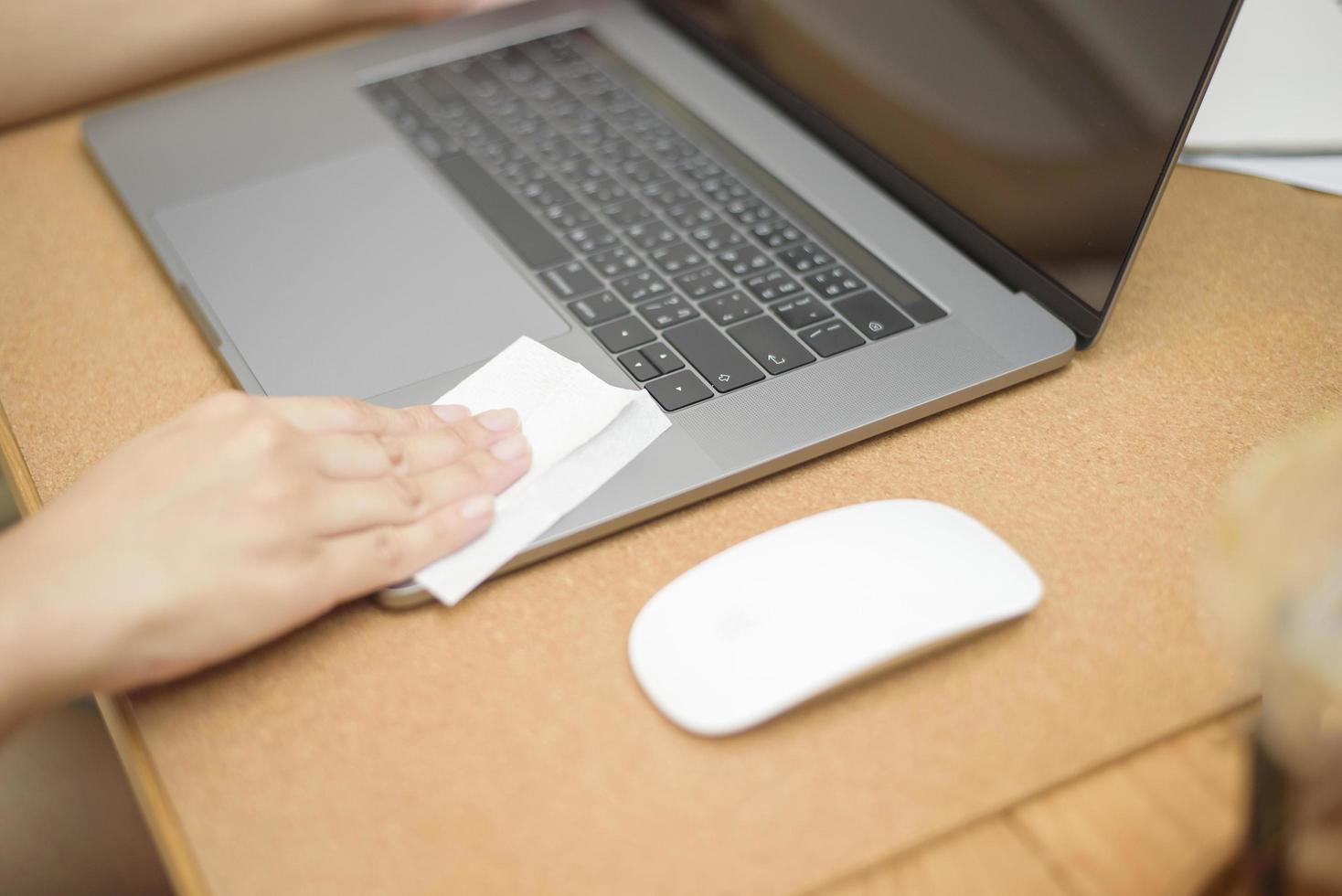 vrouw maakt laptop schoon met alcoholspray foto