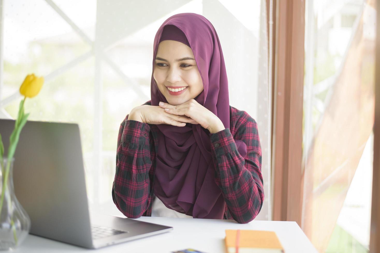 moslimvrouw met hijab werkt met laptopcomputer in coffeeshop foto