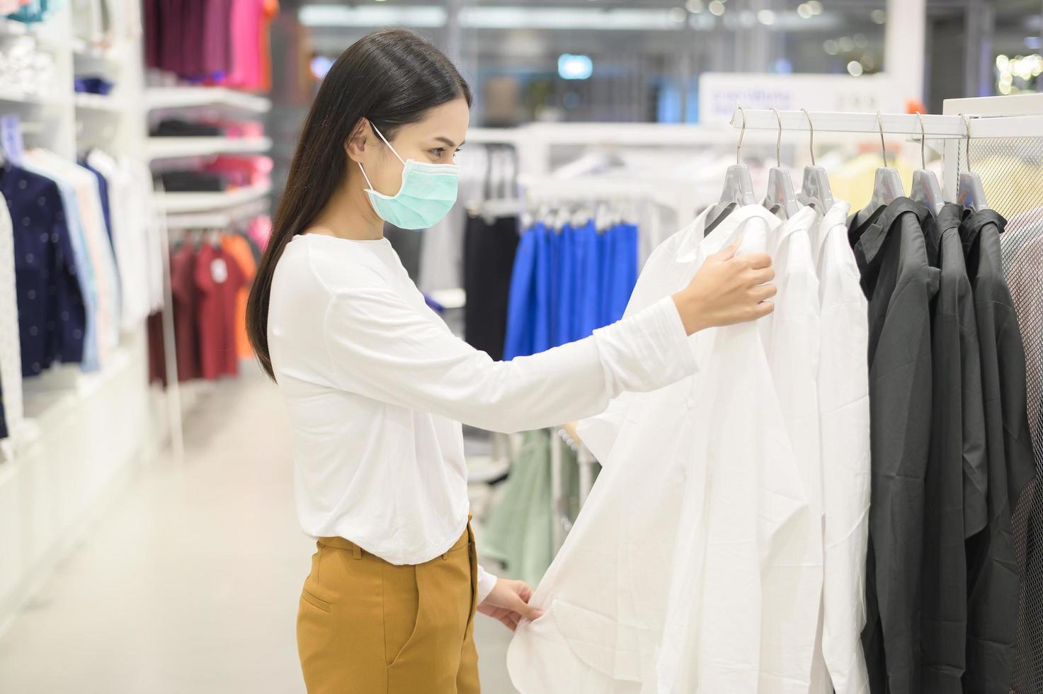 vrouw met beschermend masker winkelen onder covid-19 pandemie in winkelcentrum, protocol voor sociale afstand, nieuw normaal concept. foto