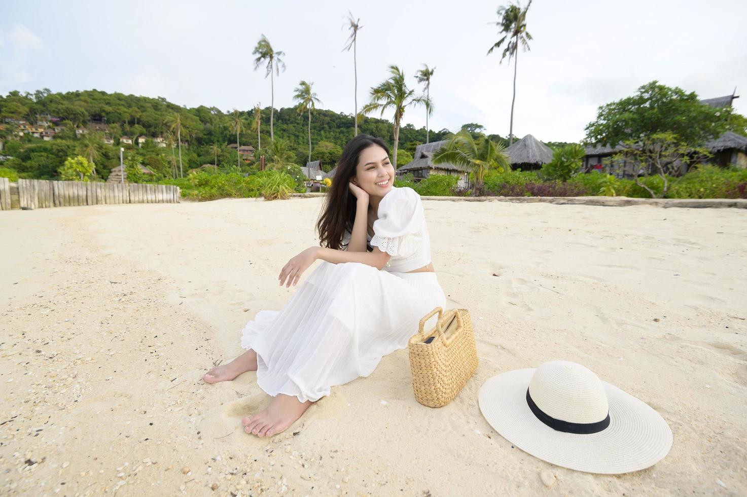 een gelukkige mooie vrouw in een witte jurk die geniet en ontspant op het strand, zomer en vakantie concept foto