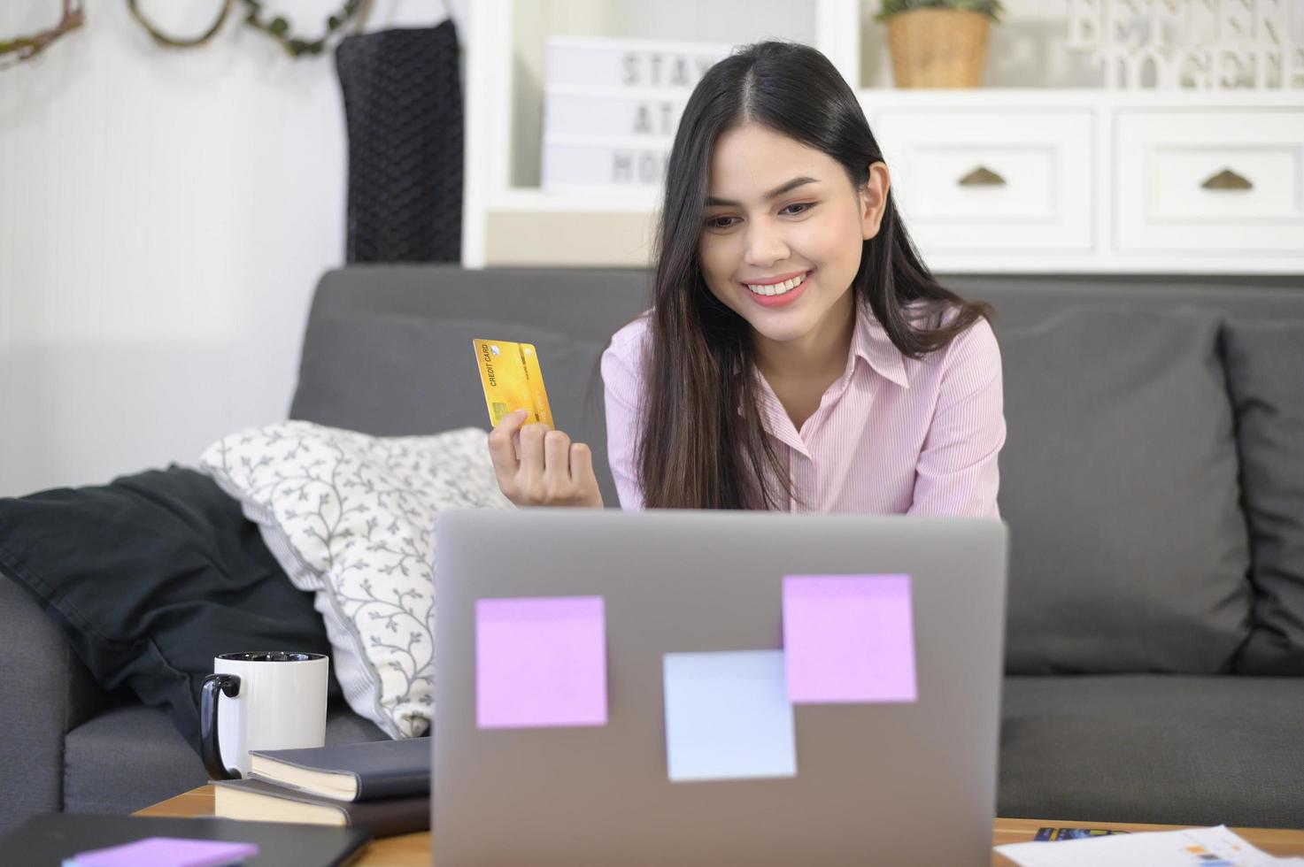 een jonge mooie vrouw gebruikt creditcard voor online winkelen op internetwebsite thuis, e-commerce concept foto