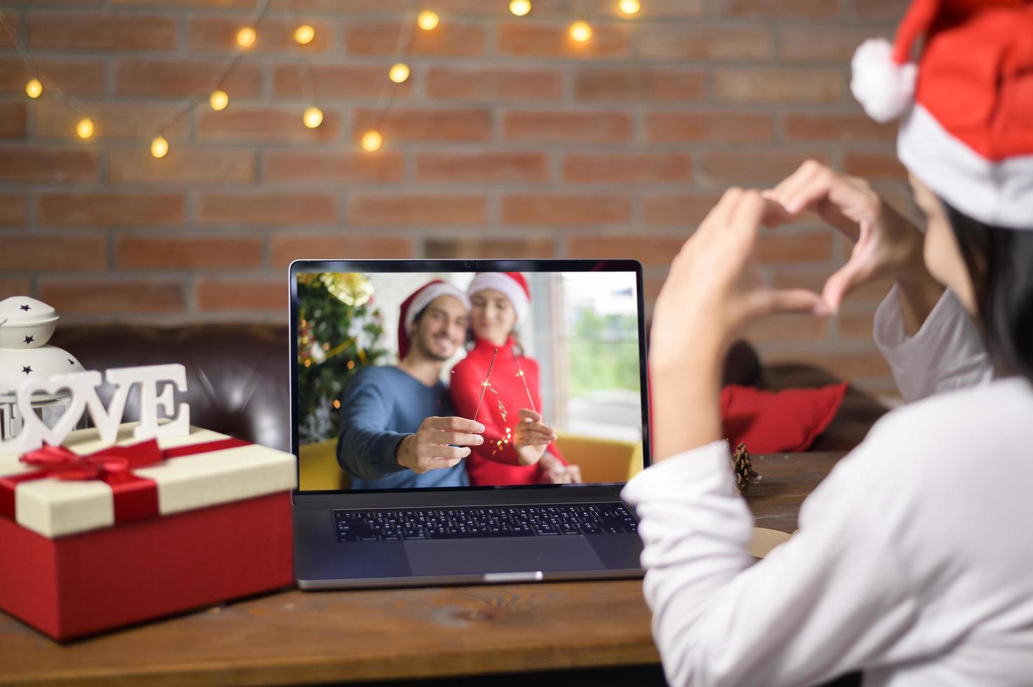 jonge lachende vrouw met rode kerstman hoed video bellen op sociaal netwerk met familie en vrienden op eerste kerstdag. foto