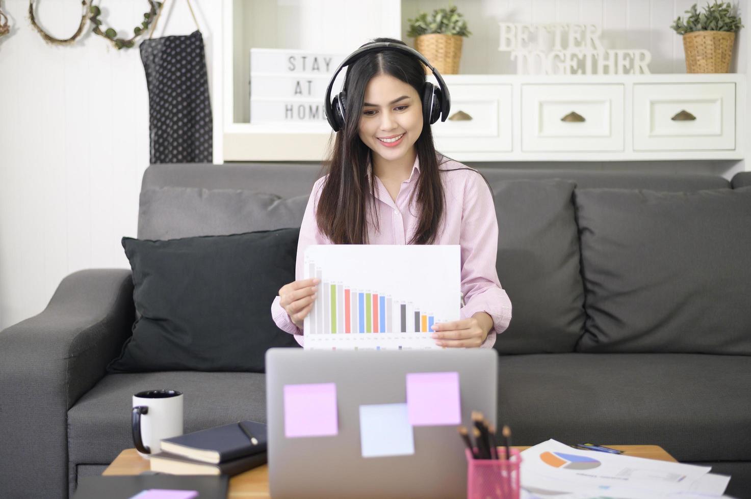 een mooie jonge vrouw die een hoofdtelefoon draagt, voert een videoconferentiegesprek via de computer thuis, een zakelijk technologieconcept. foto