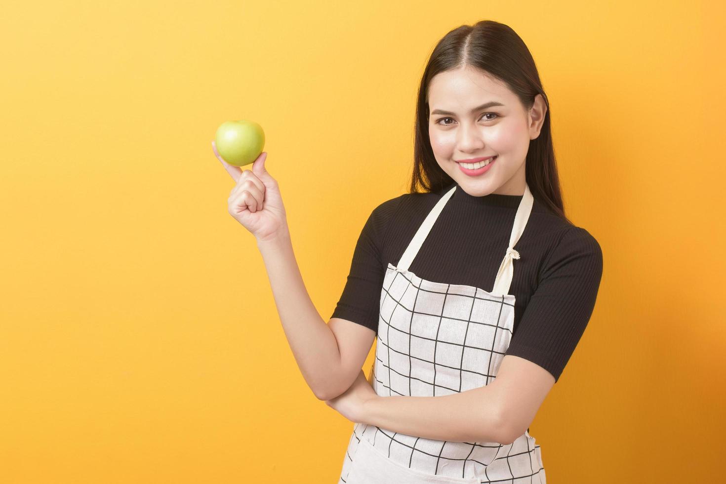 mooie vrouw houdt appel op gele achtergrond foto