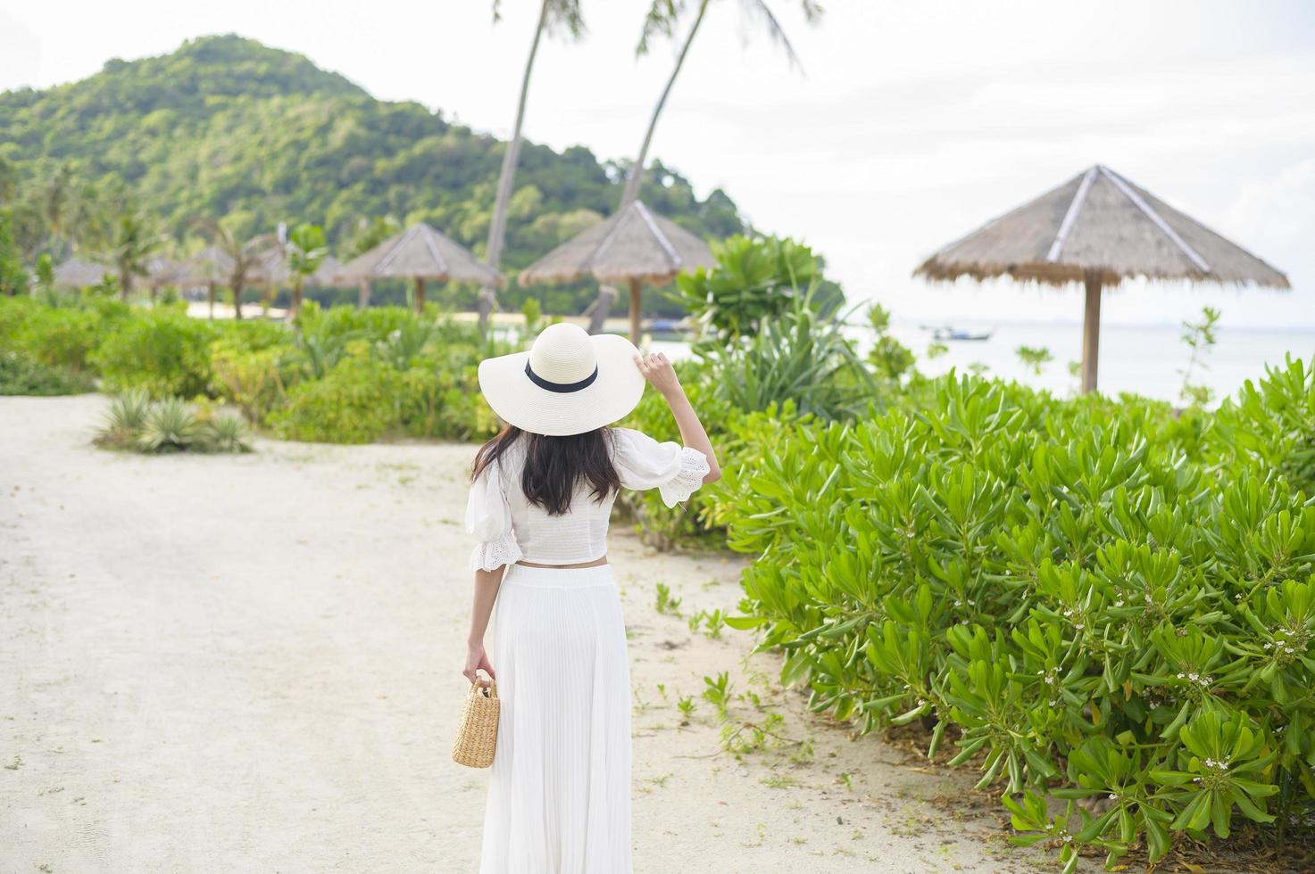 een gelukkige mooie vrouw in een witte jurk die geniet en ontspant op het strand, zomer en vakantie concept foto