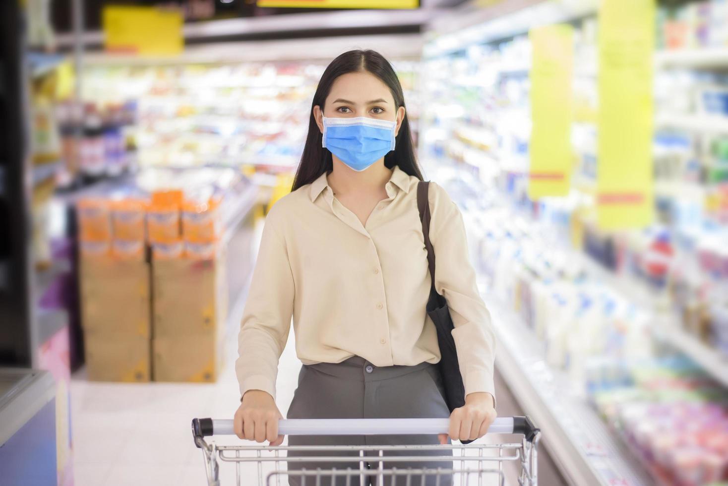 vrouw winkelt in supermarkt met gezichtsmasker foto