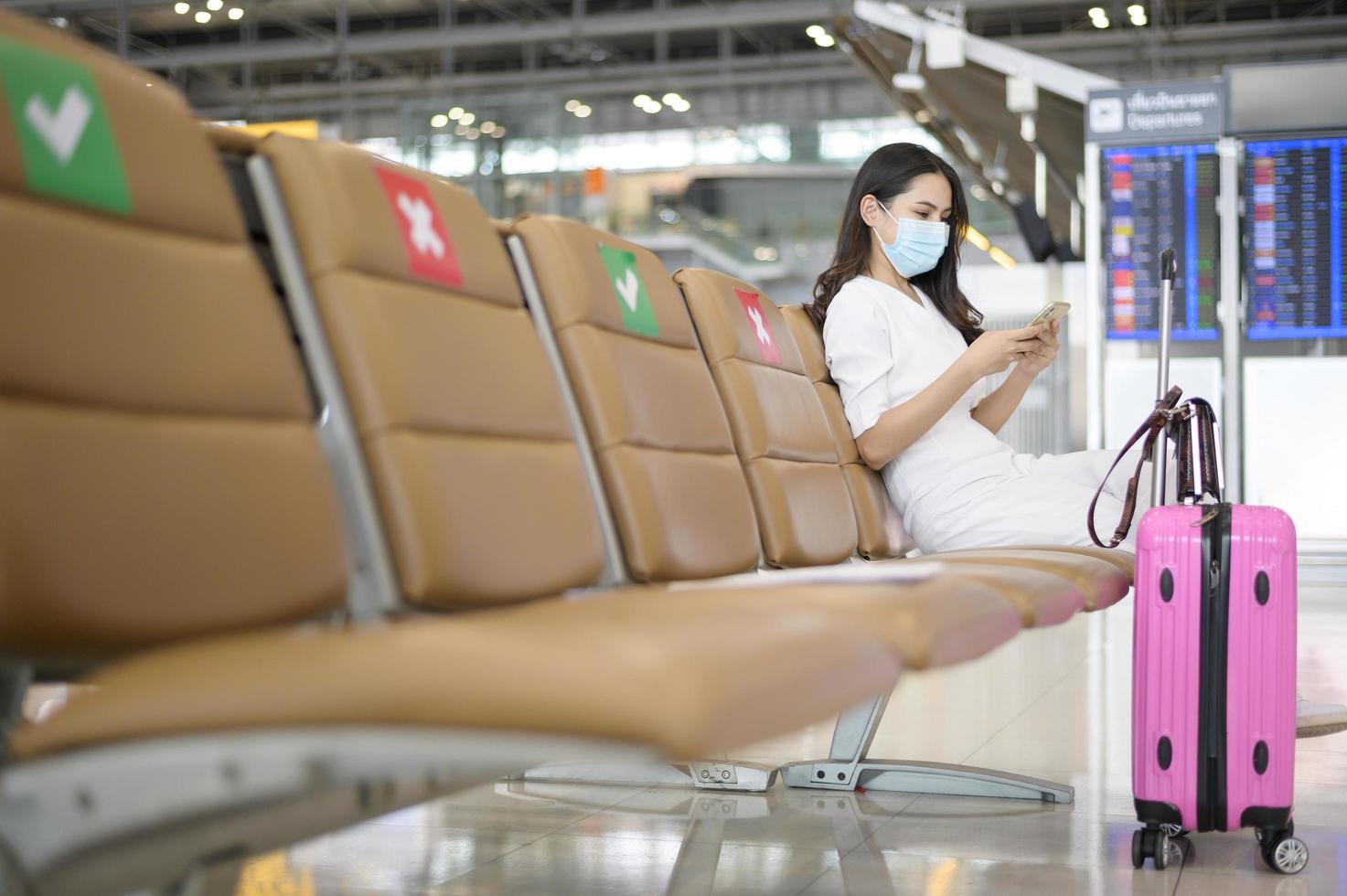 een reizigersvrouw draagt een beschermend masker op de internationale luchthaven, reist onder covid-19 pandemie, veiligheidsreizen, protocol voor sociale afstand, nieuw normaal reisconcept foto