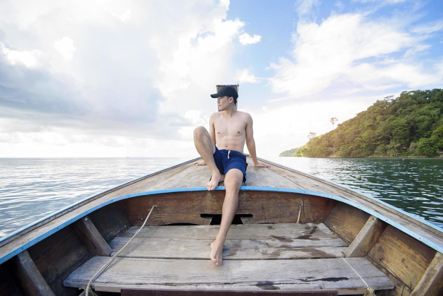 weergave van man in zwembroek genietend op Thaise traditionele longtailboot over prachtige bergen en oceaan, phi phi-eilanden, thailand foto