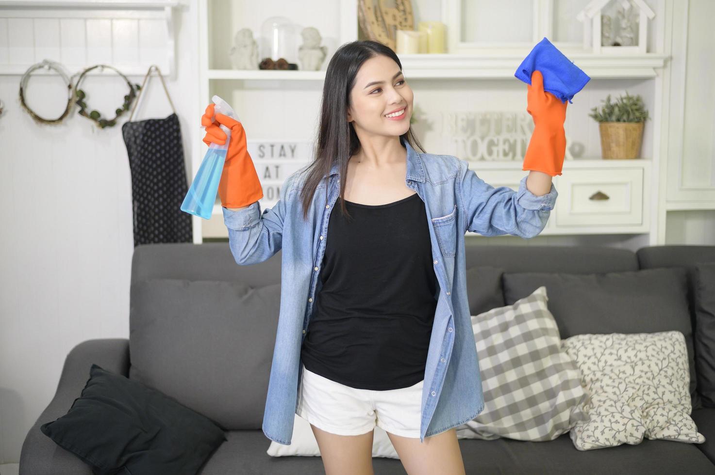 een vrouw met schoonmaakhandschoenen die alcoholspray gebruikt om het huis schoon te maken, gezond en medisch, covid-19 bescherming thuis concept foto