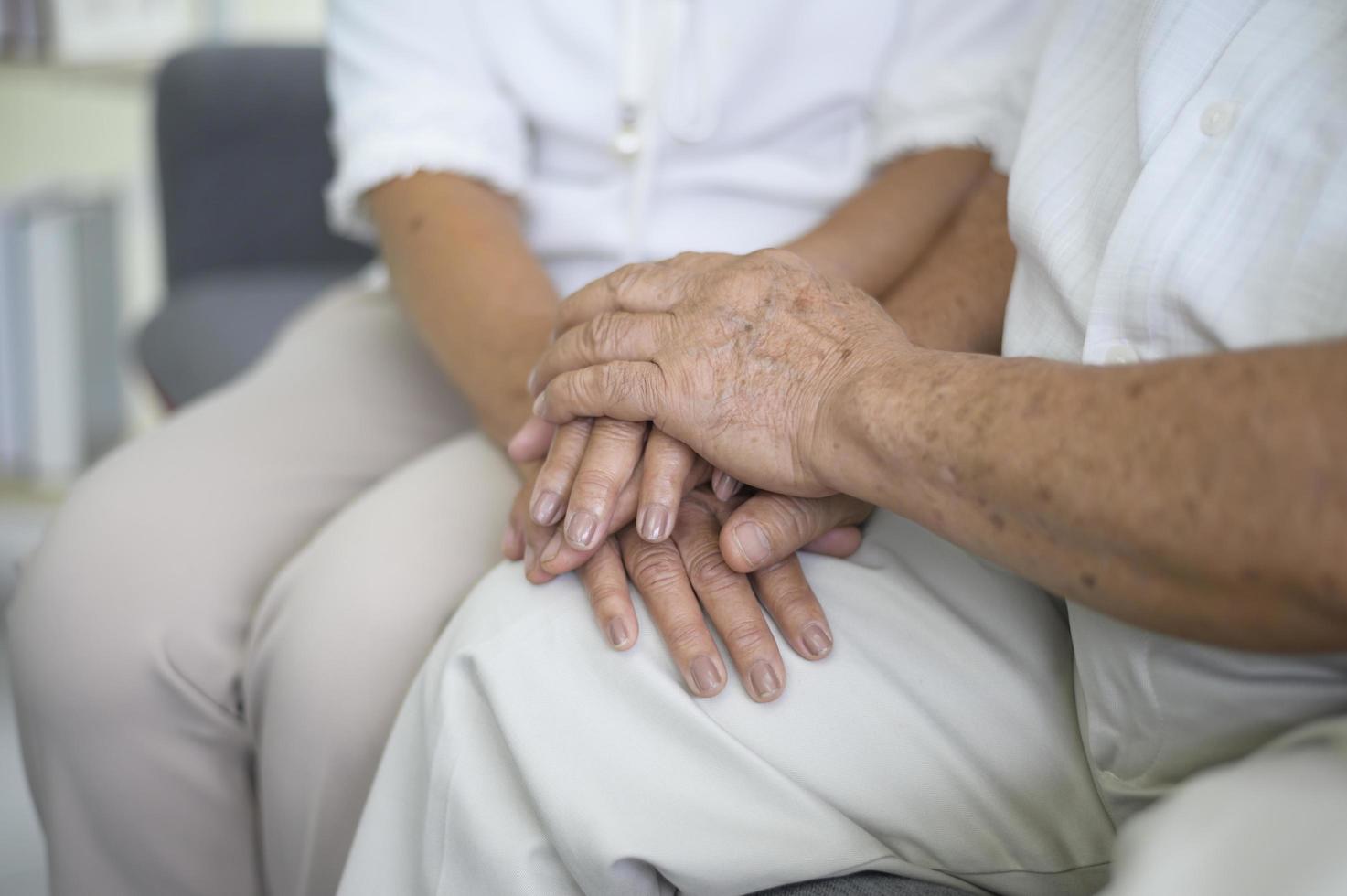 close-up van oudere handen die elkaar vasthouden, grootvaderhanden houden omahanden vast, samen, familieconcept foto