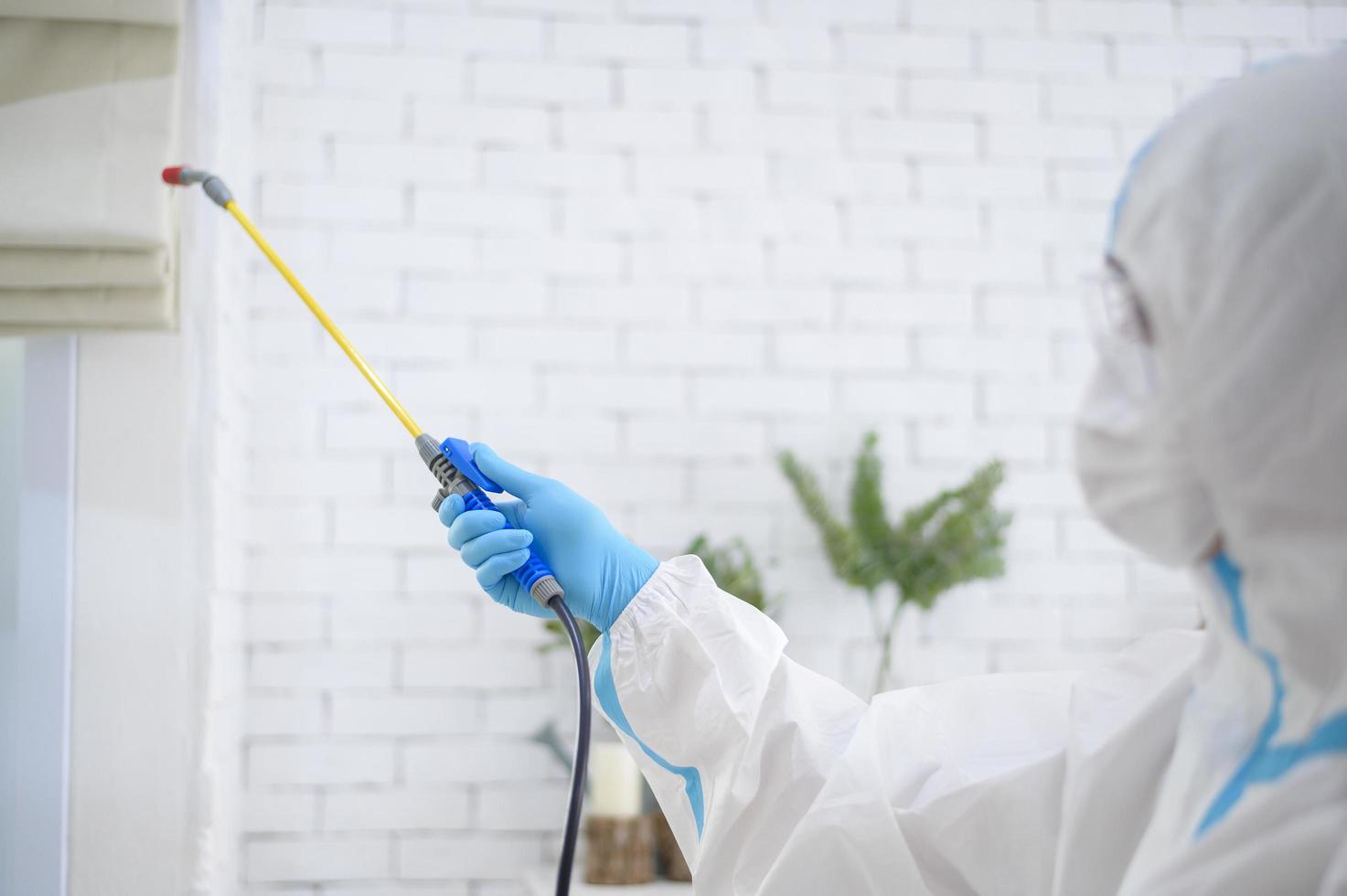 een medisch personeel in pbm-pak gebruikt desinfecterende spray in de woonkamer, covid-19-bescherming, desinfectieconcept. foto