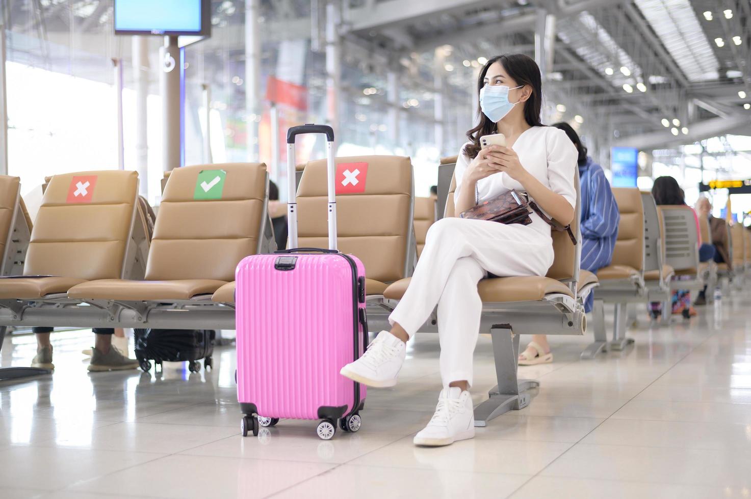 een reizigersvrouw draagt een beschermend masker op de internationale luchthaven, reist onder covid-19 pandemie, veiligheidsreizen, protocol voor sociale afstand, nieuw normaal reisconcept foto