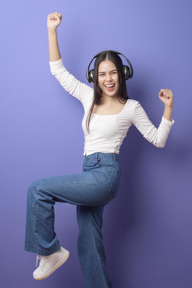 jonge vrouw luistert naar muziek op paarse achtergrond foto