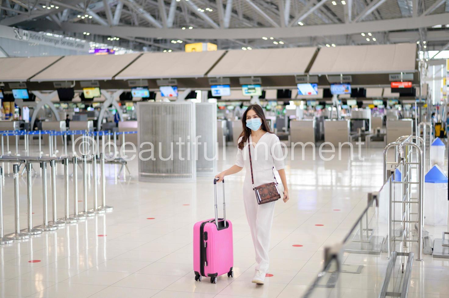 een reizigersvrouw draagt een beschermend masker op de internationale luchthaven, reist onder covid-19 pandemie, veiligheidsreizen, protocol voor sociale afstand, nieuw normaal reisconcept foto