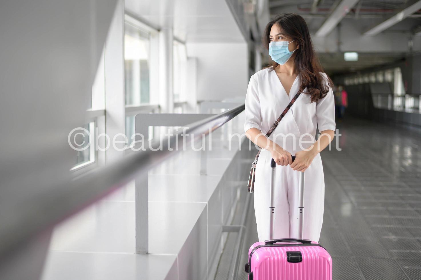 een reizigersvrouw draagt een beschermend masker op de internationale luchthaven, reist onder covid-19 pandemie, veiligheidsreizen, protocol voor sociale afstand, nieuw normaal reisconcept foto