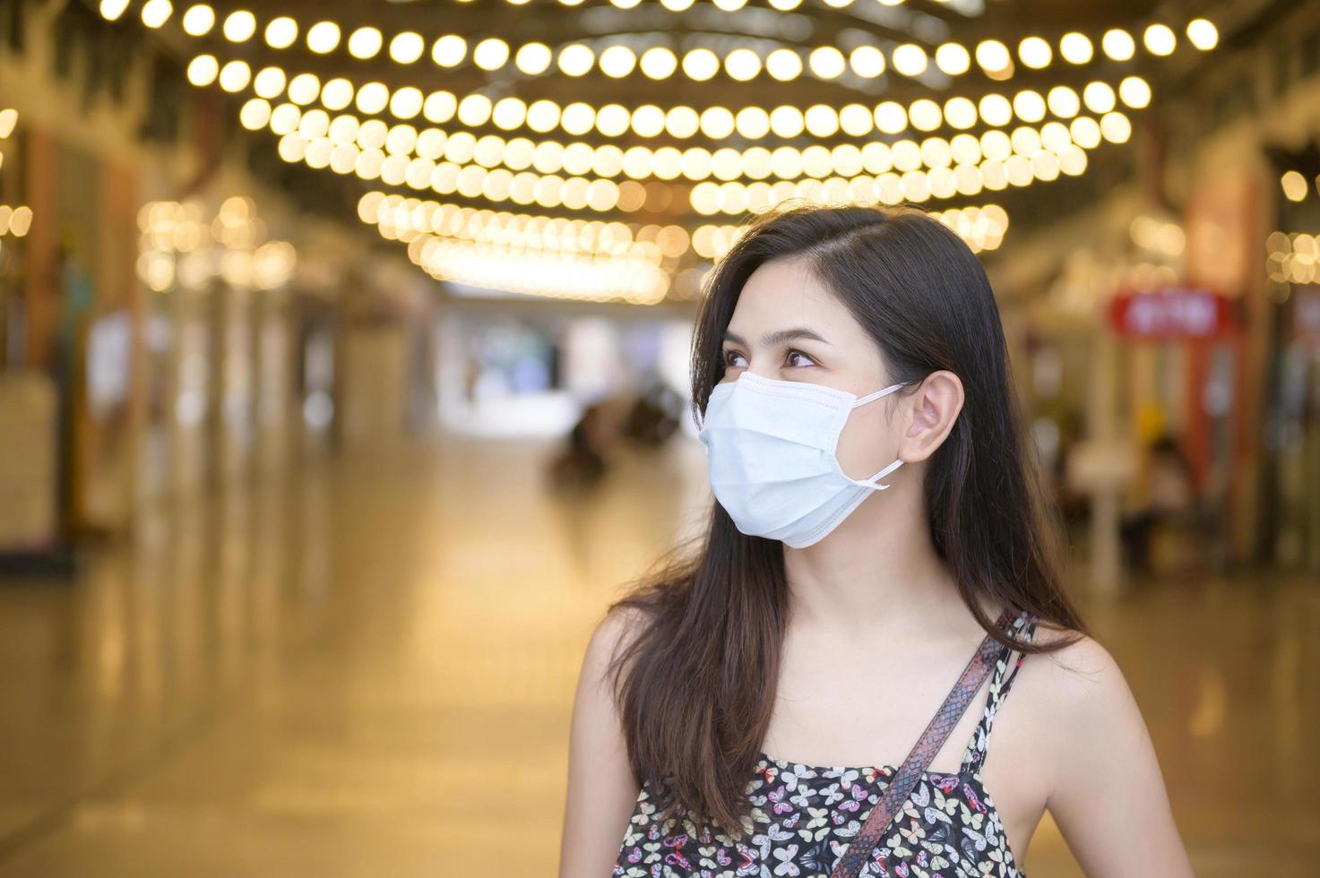 een jonge aziatische vrouw draagt een beschermend masker dat winkelt in het winkelcentrum, bescherming tegen het coronavirus, een nieuw normaal levensstijlconcept foto