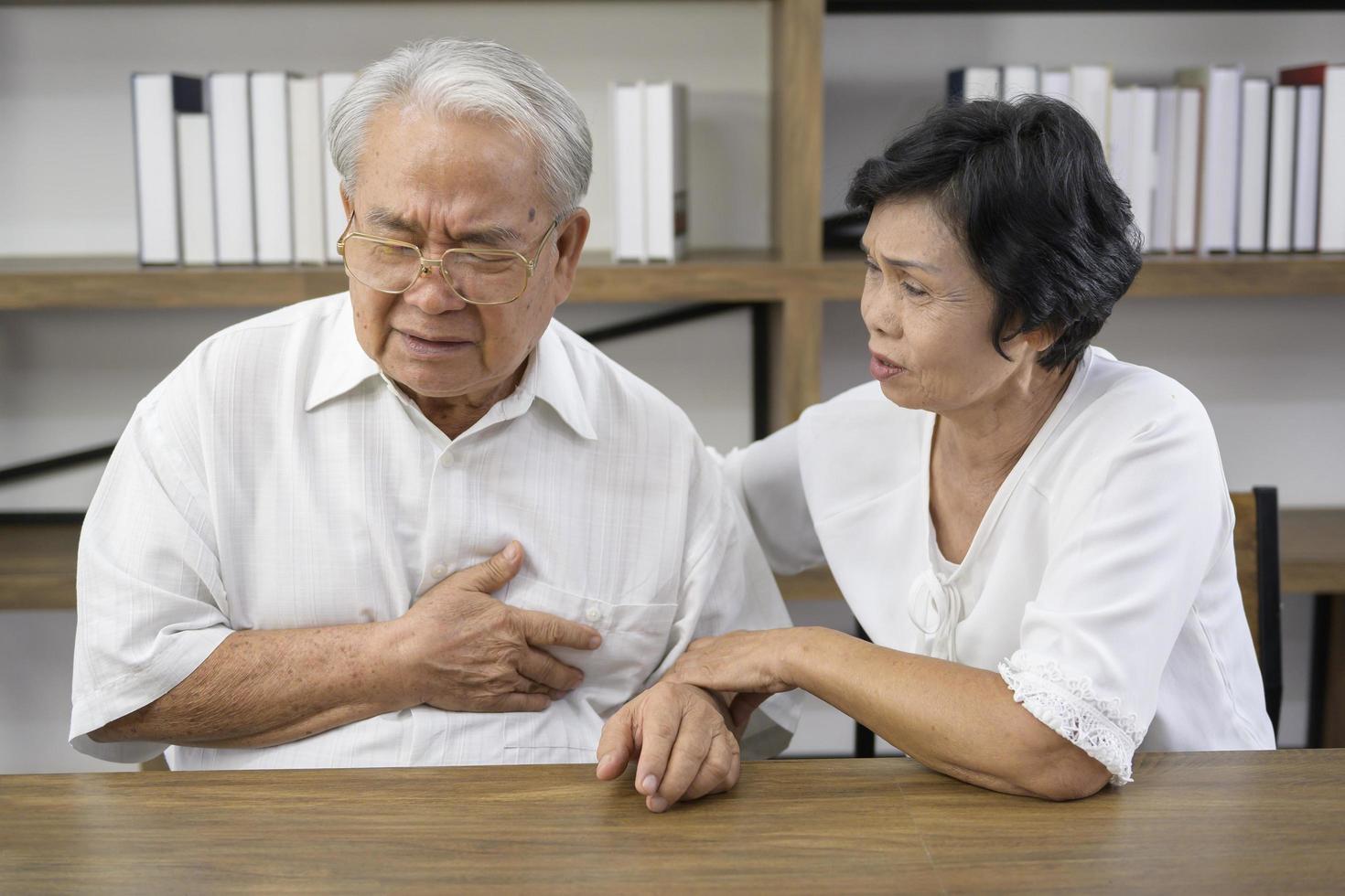 senior aziatische man met hartaanval en pijn op de borst thuis, gezondheidsconcept. foto