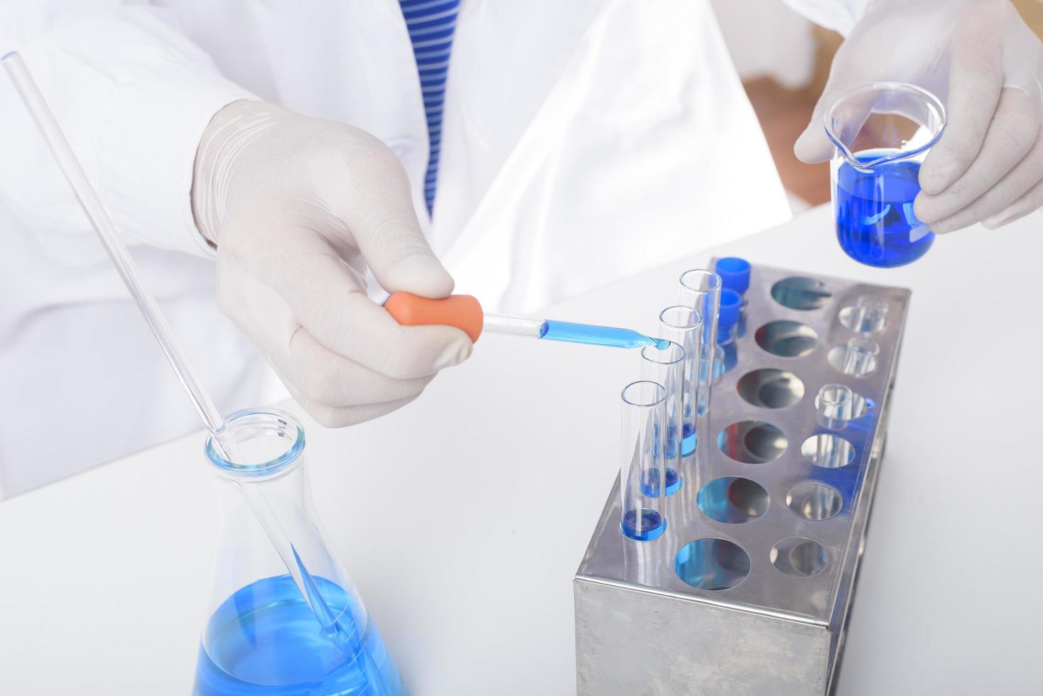 close-up van de wetenschapper test en onderzoekt wat blauwe vloeibare chemische stof in laboratorium geïsoleerde witte achtergrond. foto