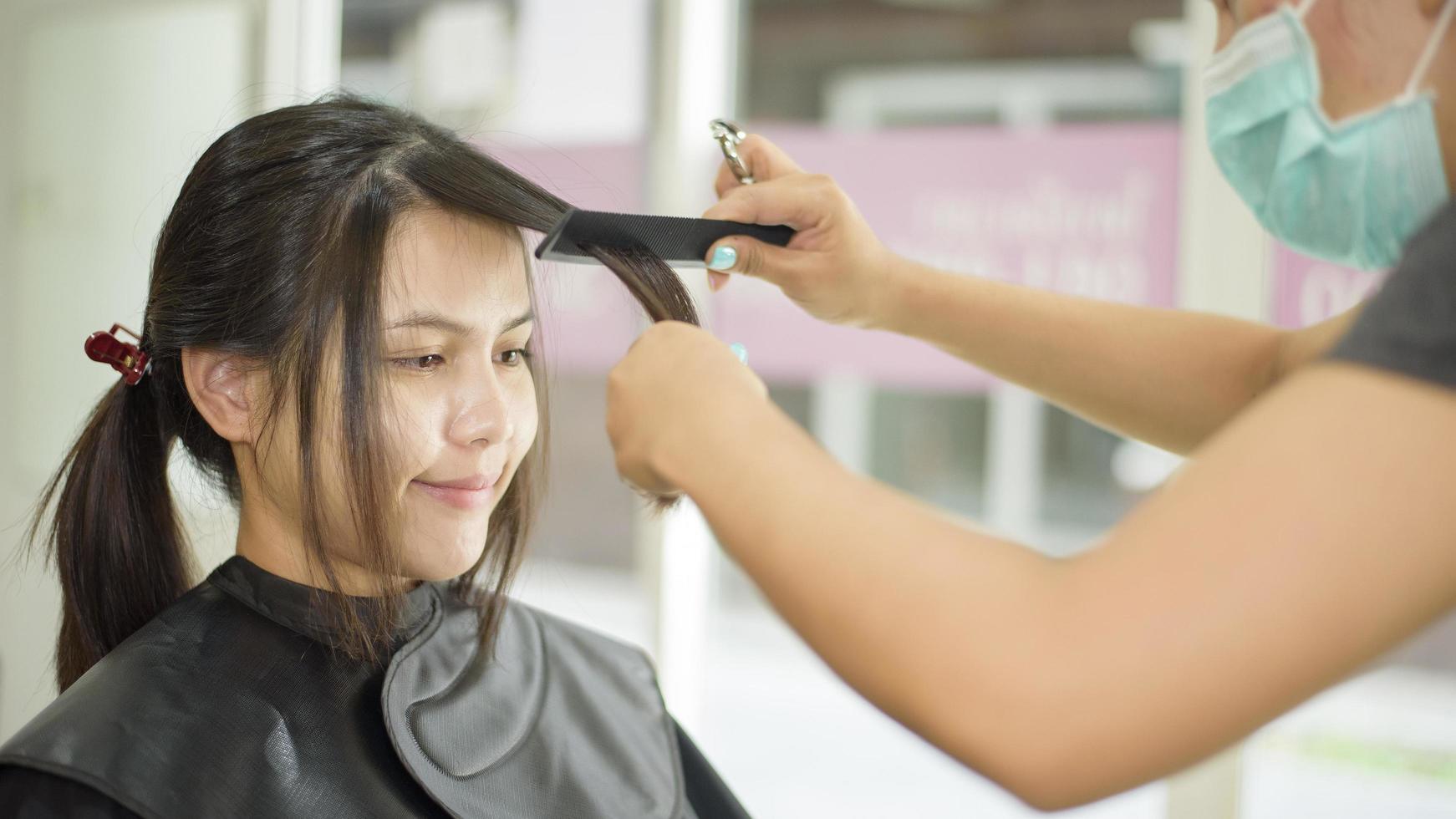 een jonge vrouw wordt geknipt in een kapsalon, salonveiligheidsconcept foto