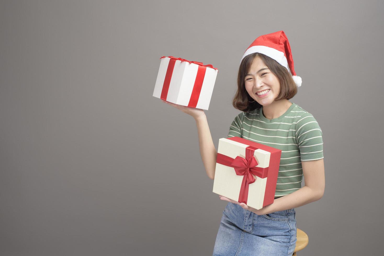 portret van een mooie vrouw met een rode kerstmuts met een geschenkdoos over studioachtergrond, kerstmis en nieuwjaarsconcept foto