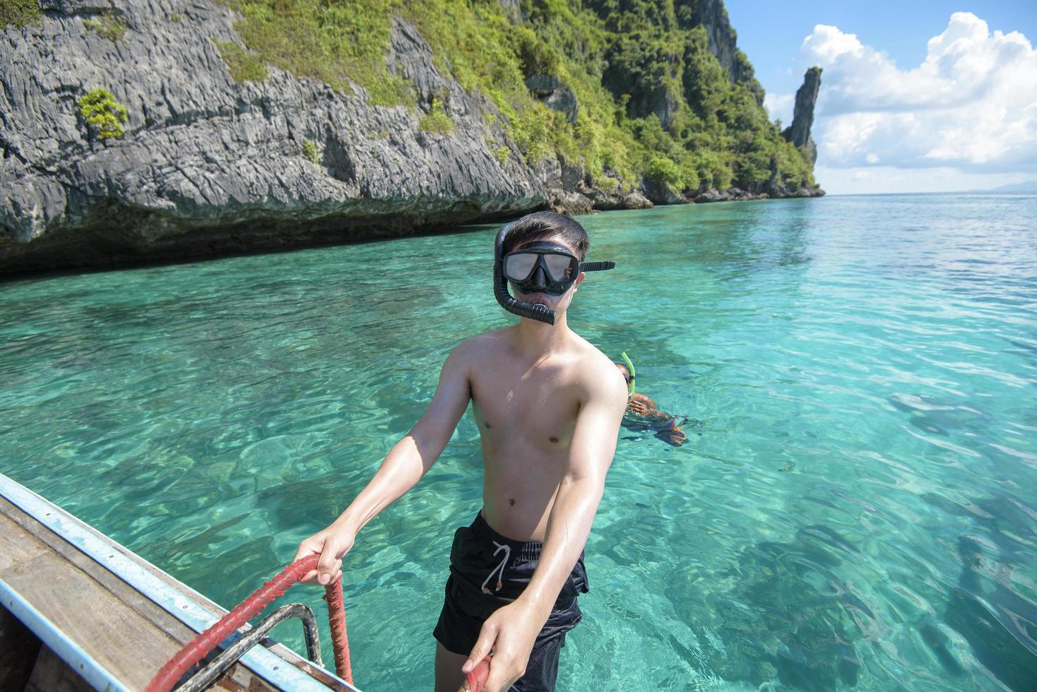 een actieve man op Thaise traditionele longtailboot is klaar om te snorkelen en te duiken, phi phi-eilanden, thailand foto