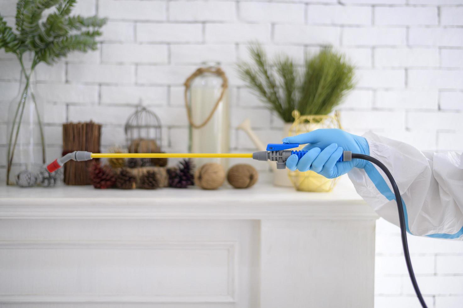 een medisch personeel in pbm-pak gebruikt desinfecterende spray in de woonkamer, covid-19-bescherming, desinfectieconcept. foto