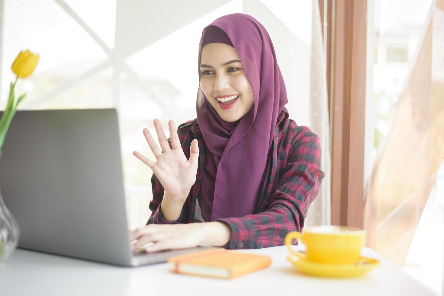 moslimvrouw met hijab werkt met laptopcomputer in coffeeshop foto