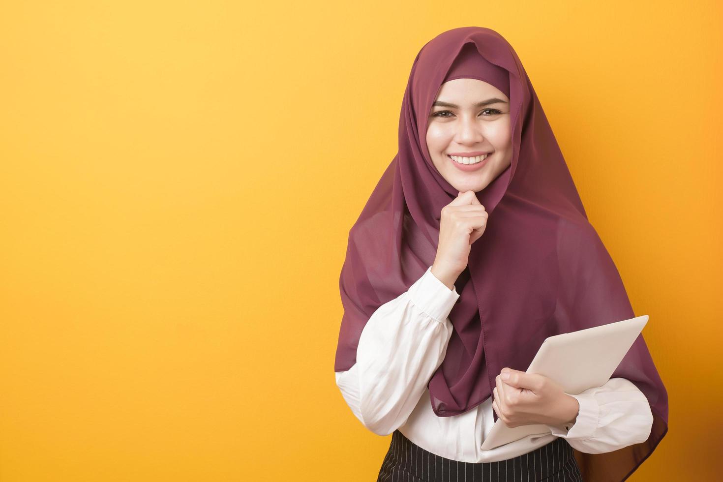 mooie universiteitsstudent met hijab portret op gele achtergrond foto