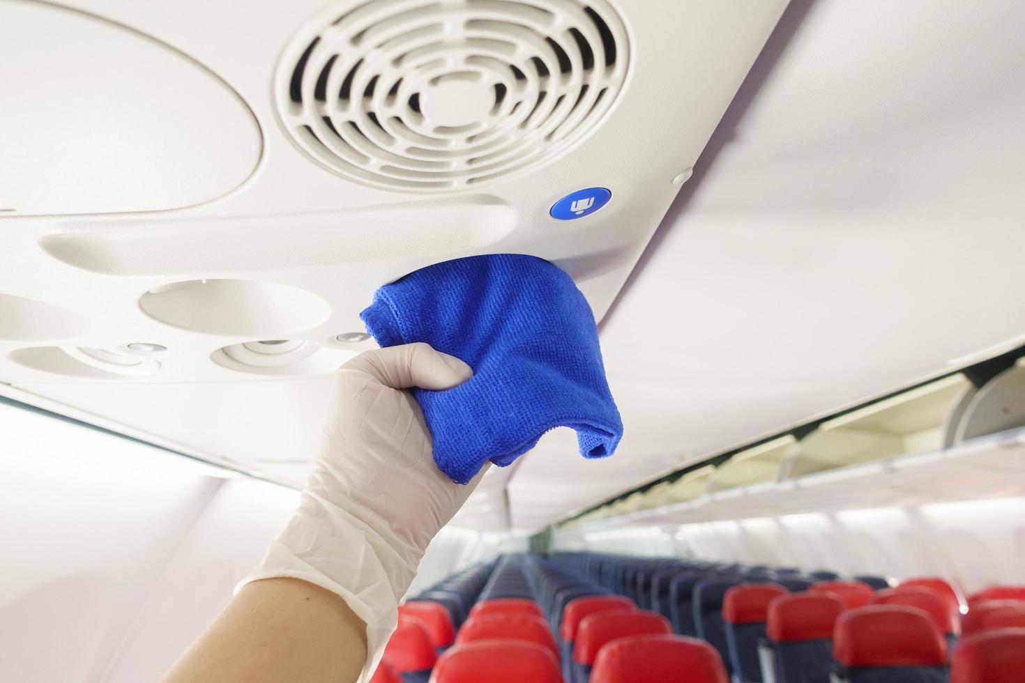 close-up hand draagt handschoenen die vliegtuigen schoonmaken voor covid-19 preventie pandemie foto