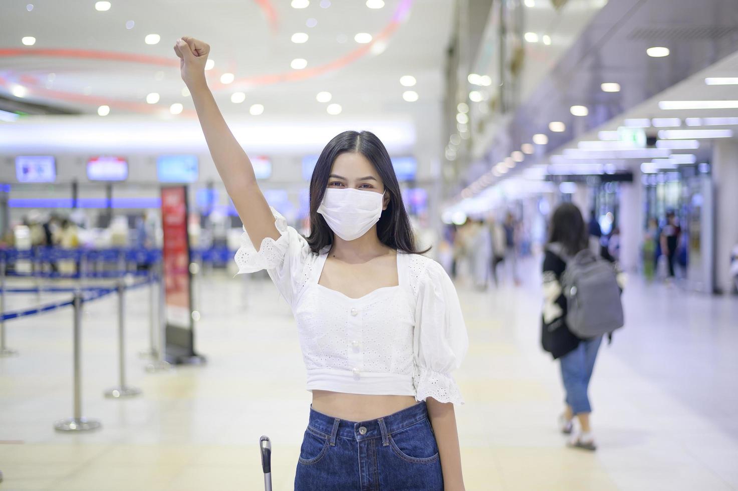 een reizigersvrouw draagt een beschermend masker op de internationale luchthaven, reist onder covid-19 pandemie, veiligheidsreizen, protocol voor sociale afstand, nieuw normaal reisconcept foto