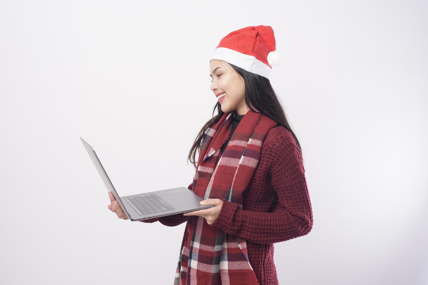 jonge lachende vrouw met rode kerstman hoed maken video-oproep op sociaal netwerk met familie en vrienden op witte achtergrond studio. foto