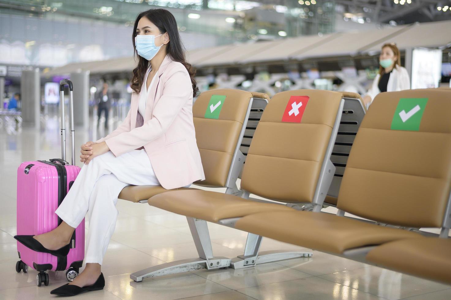 een zakenvrouw draagt een beschermend masker op de internationale luchthaven, reist onder covid-19 pandemie, veiligheidsreizen, protocol voor sociale afstand, nieuw normaal reisconcept foto