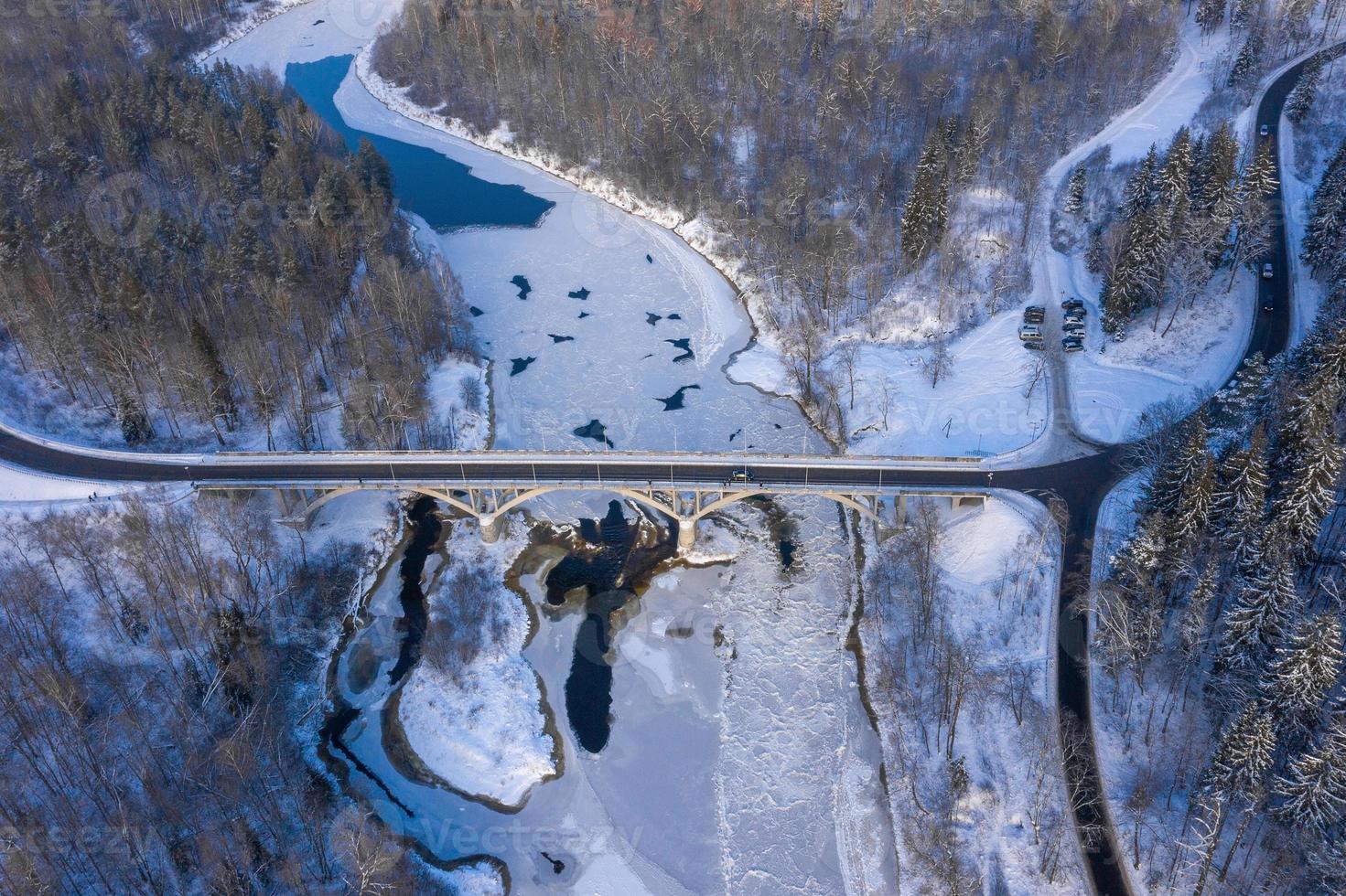 winterseizoen luchtfoto van boven naar beneden uitzicht op een brug met een rechte lijnweg over de rivier foto